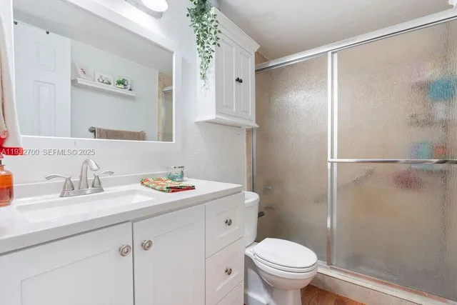 a bathroom with a granite countertop sink toilet and shower