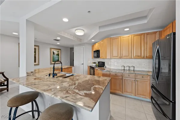 a large kitchen with stainless steel appliances kitchen island granite countertop a refrigerator and a stove top oven