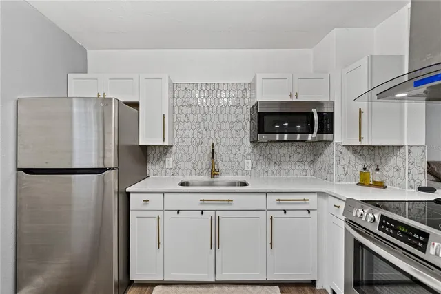 a kitchen with a sink a refrigerator a microwave and cabinets