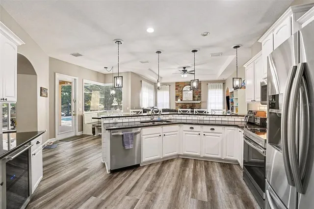 a kitchen with stainless steel appliances granite countertop hardwood floor sink stove and refrigerator