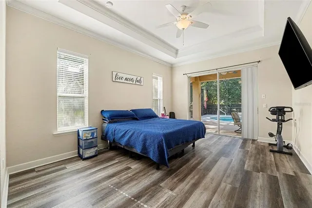 a spacious bedroom with a bed and a flat tv screen on dresser