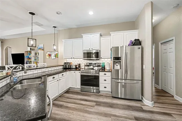 a kitchen with stainless steel appliances granite countertop a refrigerator a sink dishwasher a stove and a refrigerator with wooden floor