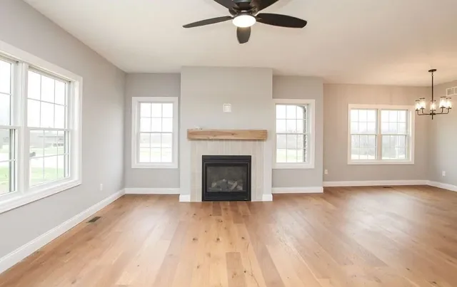 a view of an empty room with wooden floor fireplace and a window