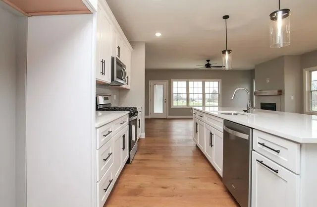 a large kitchen with stainless steel appliances granite countertop a sink and a wooden floors