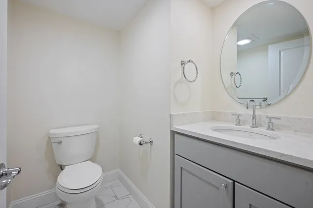 a bathroom with a granite countertop toilet sink and mirror