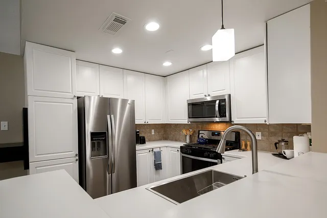 a kitchen with stainless steel appliances granite countertop a refrigerator a sink a stove a microwave and a refrigerator