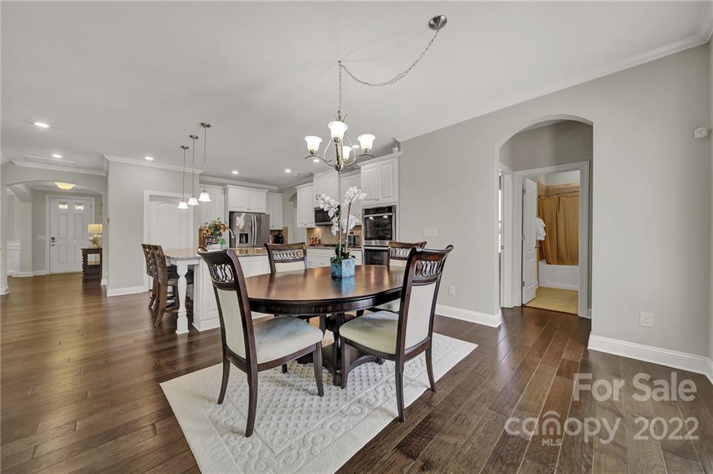 207 Kingsdown Avenue Charlotte, NC 28270 - Photo 11 of 48 a dining room with wooden floor a chandelier a wooden table and chairs