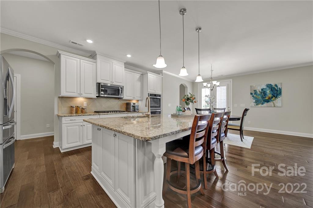 207 Kingsdown Avenue Charlotte, NC 28270 - Photo 12 of 48 a kitchen with kitchen island granite countertop wooden floor cabinets and refrigerator