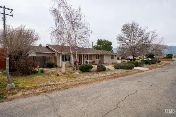 a view of a house with a yard and large trees