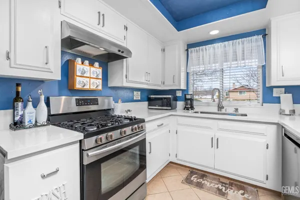 a kitchen with stainless steel appliances granite countertop a sink a stove cabinets and a window