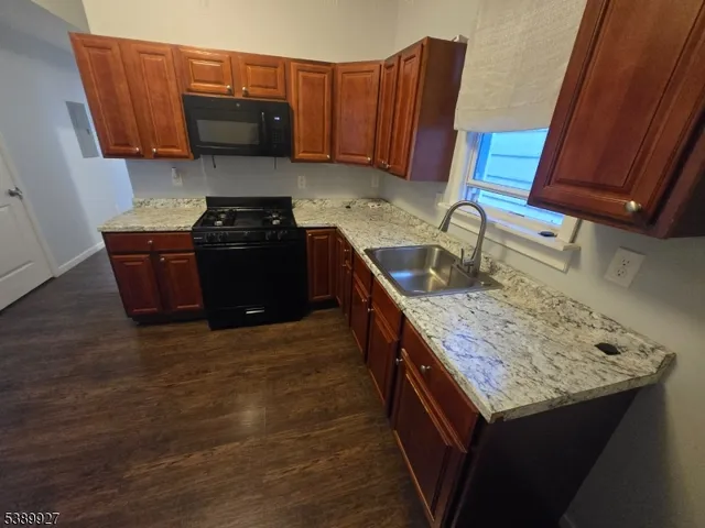 a kitchen with granite countertop a stove and a wooden cabinets