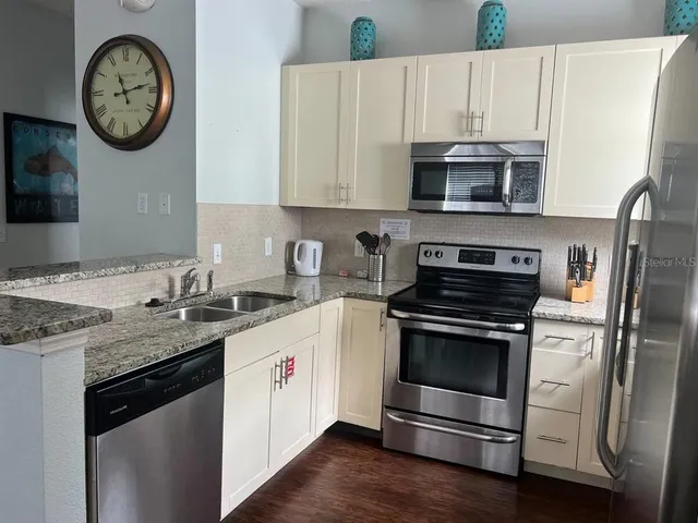 a kitchen with stainless steel appliances granite countertop a stove a microwave a sink and cabinets