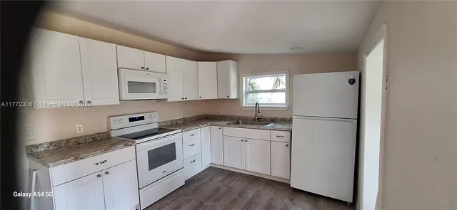 a kitchen with white cabinets white stainless steel appliances and sink