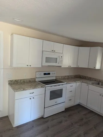 a kitchen with granite countertop white cabinets and white appliances