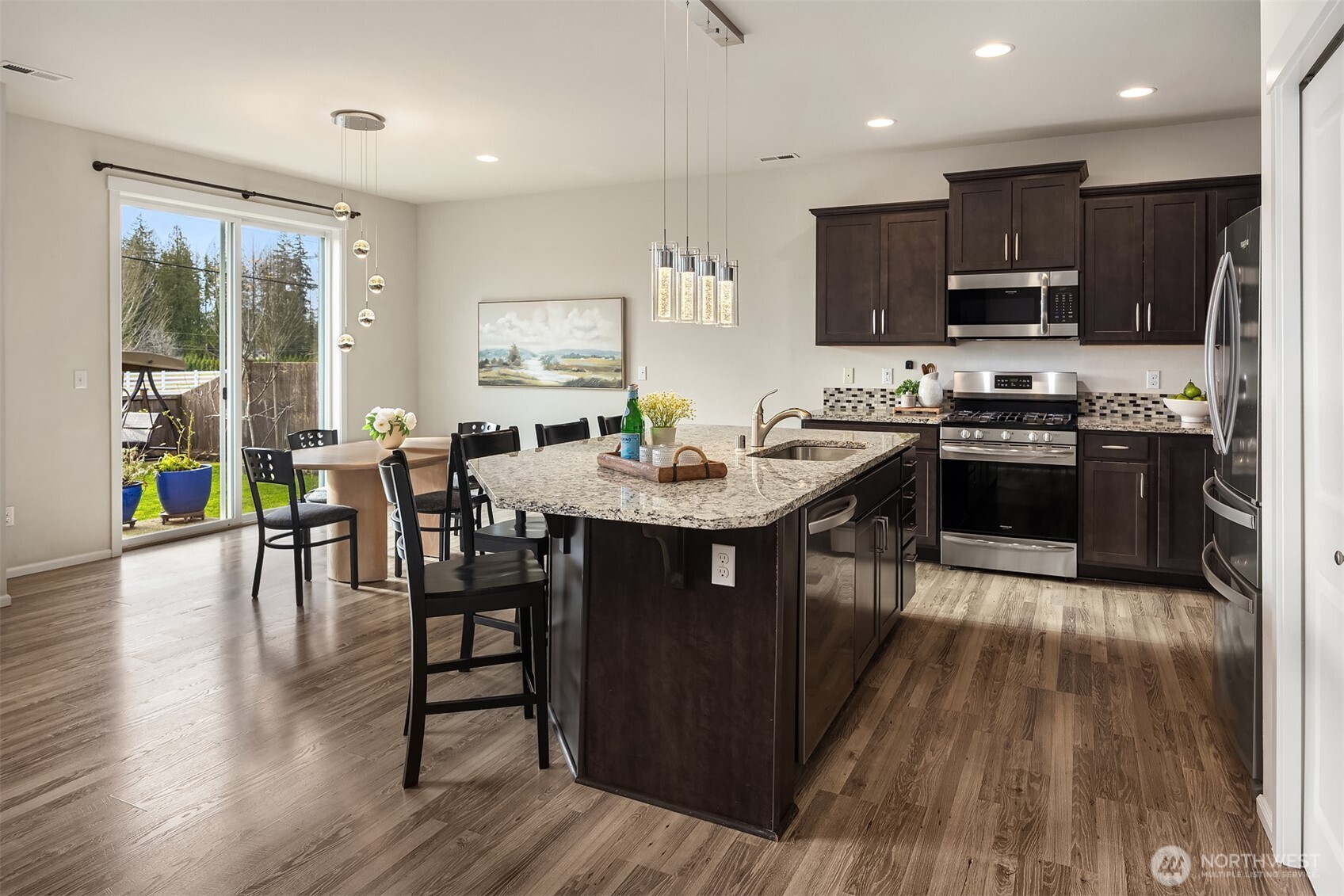 17604 Quartz Street Granite Falls, WA 98252 - Photo 9 of 40 a kitchen with stainless steel appliances granite countertop wooden floors a stove a sink a dining table and chairs