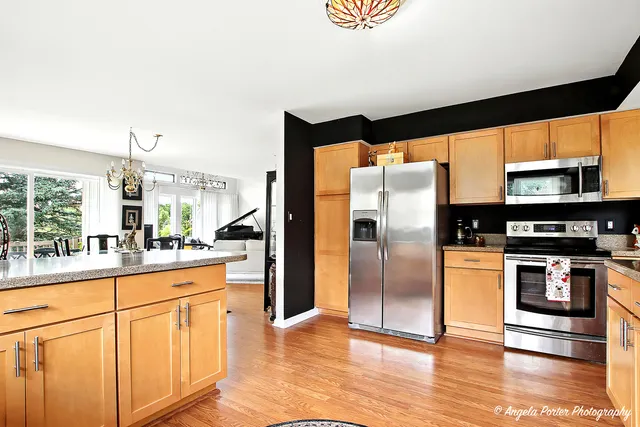 a kitchen with stainless steel appliances granite countertop a refrigerator a stove and a sink with wooden floor