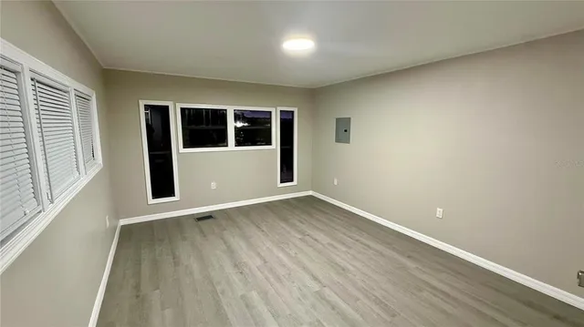 an empty room with wooden floor and windows