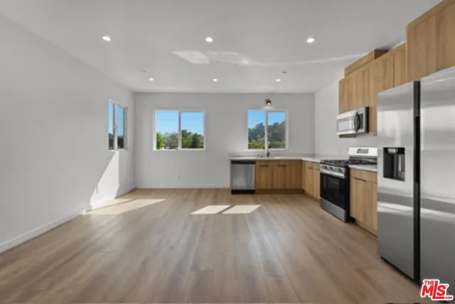 a kitchen with stainless steel appliances granite countertop a refrigerator a stove and a wooden floors