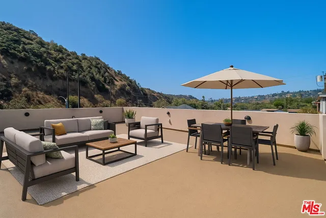 a view of a patio with chairs and a table and chairs under an umbrella