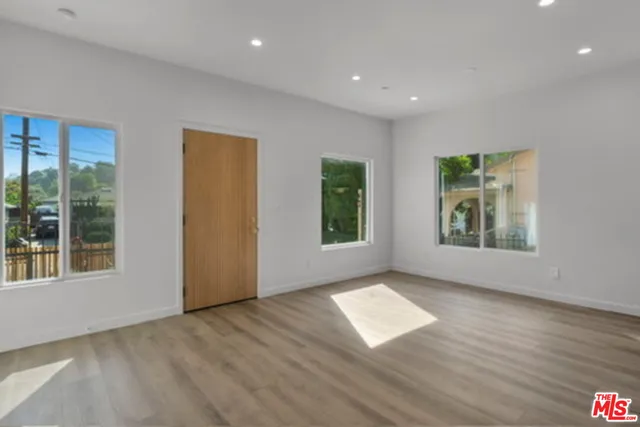 a view of an empty room with glass door and wooden floor