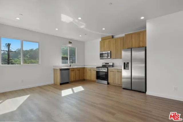 a view of kitchen with stainless steel appliances kitchen island wooden floor and window