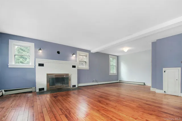an empty room with wooden floor a fireplace and windows
