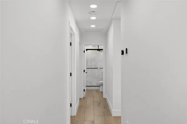 a view of a hallway with wooden floor and a bathroom
