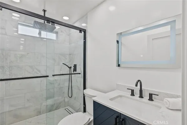 a bathroom with a granite countertop sink toilet and shower