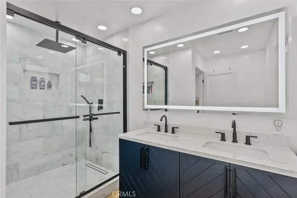 a bathroom with a double vanity sink mirror and shower
