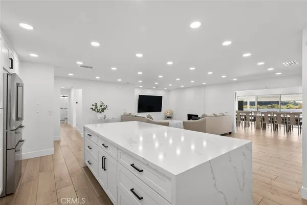 a large white kitchen with a large island in the center