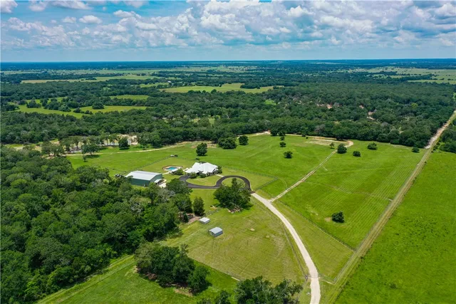 an aerial view of residential houses with outdoor space and trees