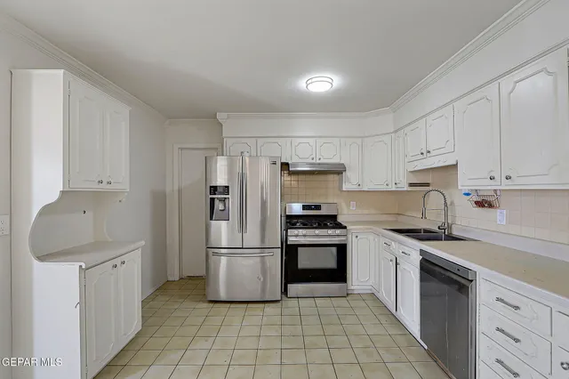 a kitchen with granite countertop a refrigerator sink and cabinets