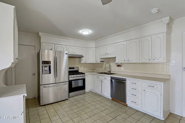 a kitchen with white cabinets and stainless steel appliances
