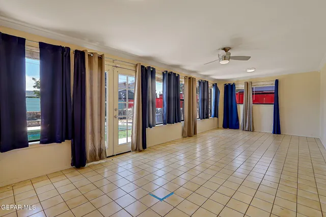 a view of an empty room with window and chandelier