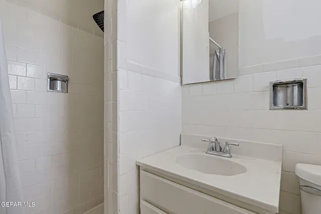 a bathroom with a granite countertop sink toilet and mirror