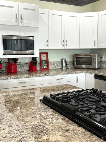 a kitchen with stainless steel appliances granite countertop a refrigerator a stove a sink and a microwave