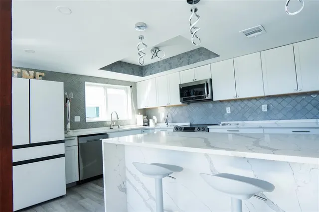 a kitchen with granite countertop white cabinets and stainless steel appliances