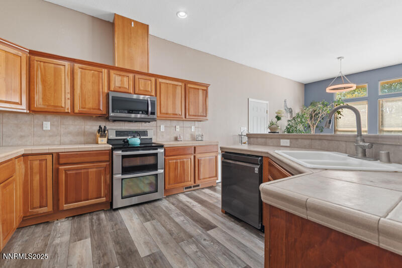 210 Nugget Avenue Dayton, NV 89403 - Photo 11 of 24 a kitchen with stainless steel appliances granite countertop a sink dishwasher stove and microwave with wooden cabinets