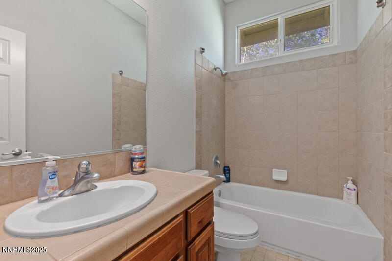 210 Nugget Avenue Dayton, NV 89403 - Photo 19 of 24 a bathroom with a granite countertop sink a toilet and a bathtub