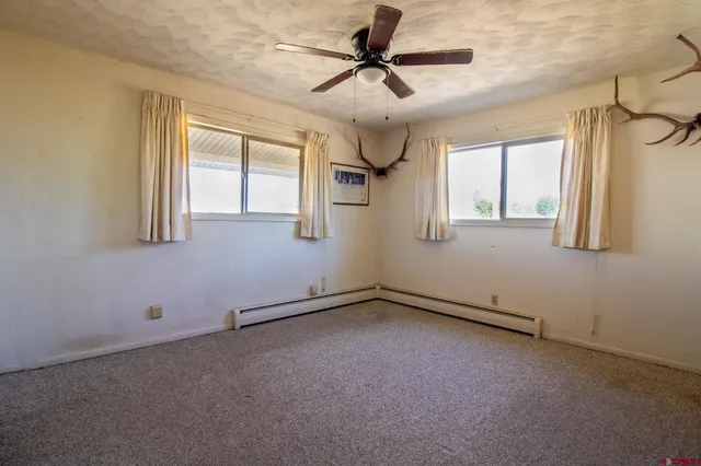 an empty room with windows and fan