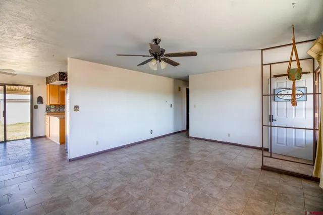 an empty room with chandelier fan and windows