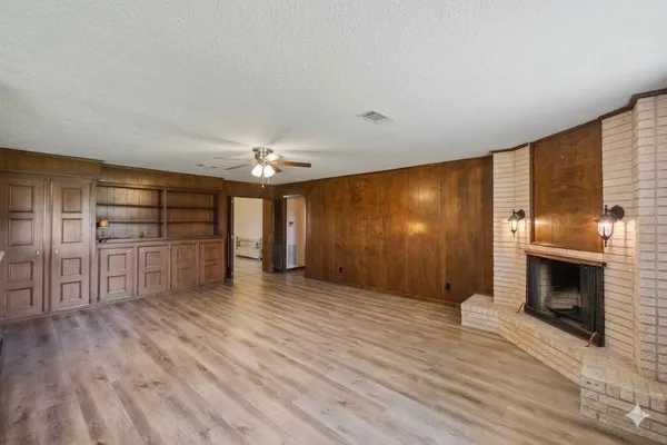 a view of empty room with wooden floor and fireplace