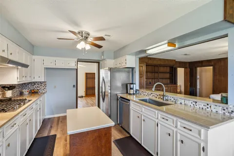 a kitchen that has a lot of cabinets in it and wooden floors