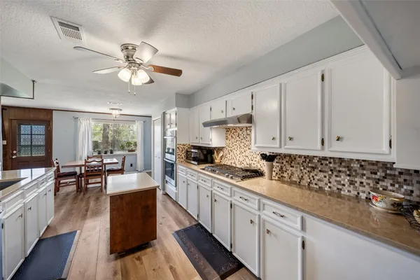 a kitchen with granite countertop a stove a sink and dishwasher with white cabinets