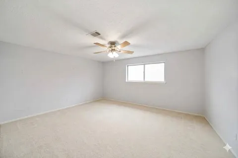 an empty room with windows and chandelier fan