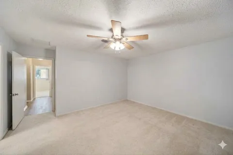 an empty room with windows and fan