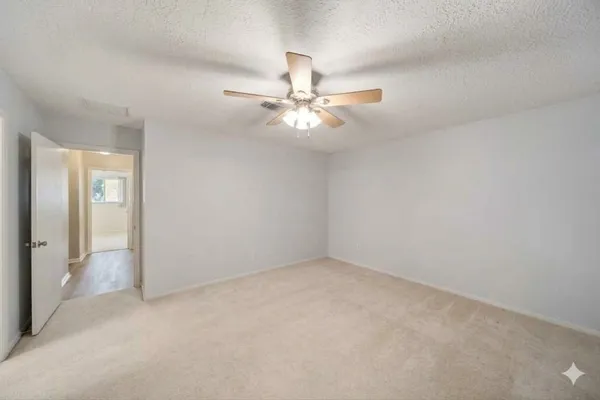 an empty room with windows and fan