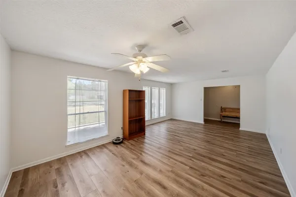 an empty room with wooden floor and windows