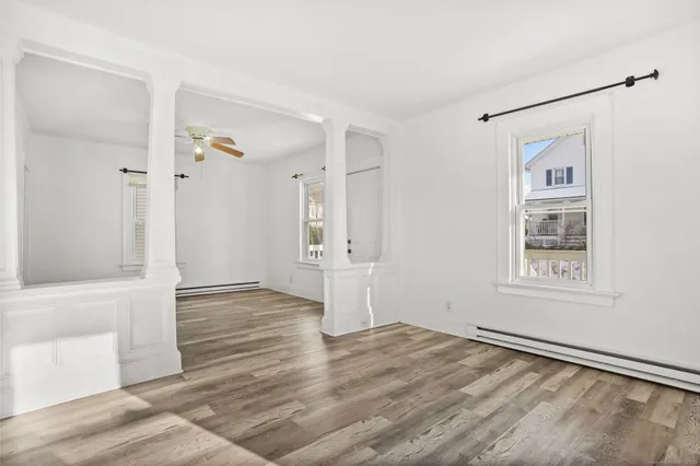 a view of an empty room with wooden floor and a window