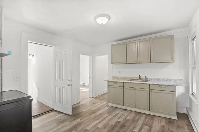 a kitchen with white cabinets sink and wooden floor